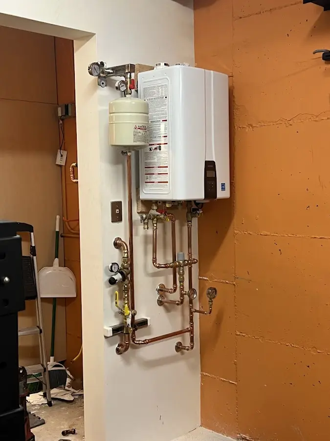 Plumbing technician inspecting water heater connections in Owatonna